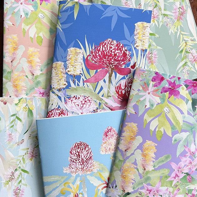 Collection of floral-patterned notebooks with vibrant colors on a wooden surface.