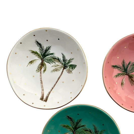 This image features the tropical mini dish in white by Carla Dinnage. The middle of the bowl has 2 green palm trees and gold mini dots. The edge of the bowl has a gold rim. 