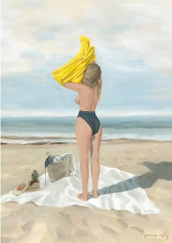 Woman in a black swimsuit holding a yellow towel on a beach with a picnic basket and fruit.
