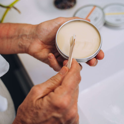 Person removing some of the sandalwood deodorant from the tin