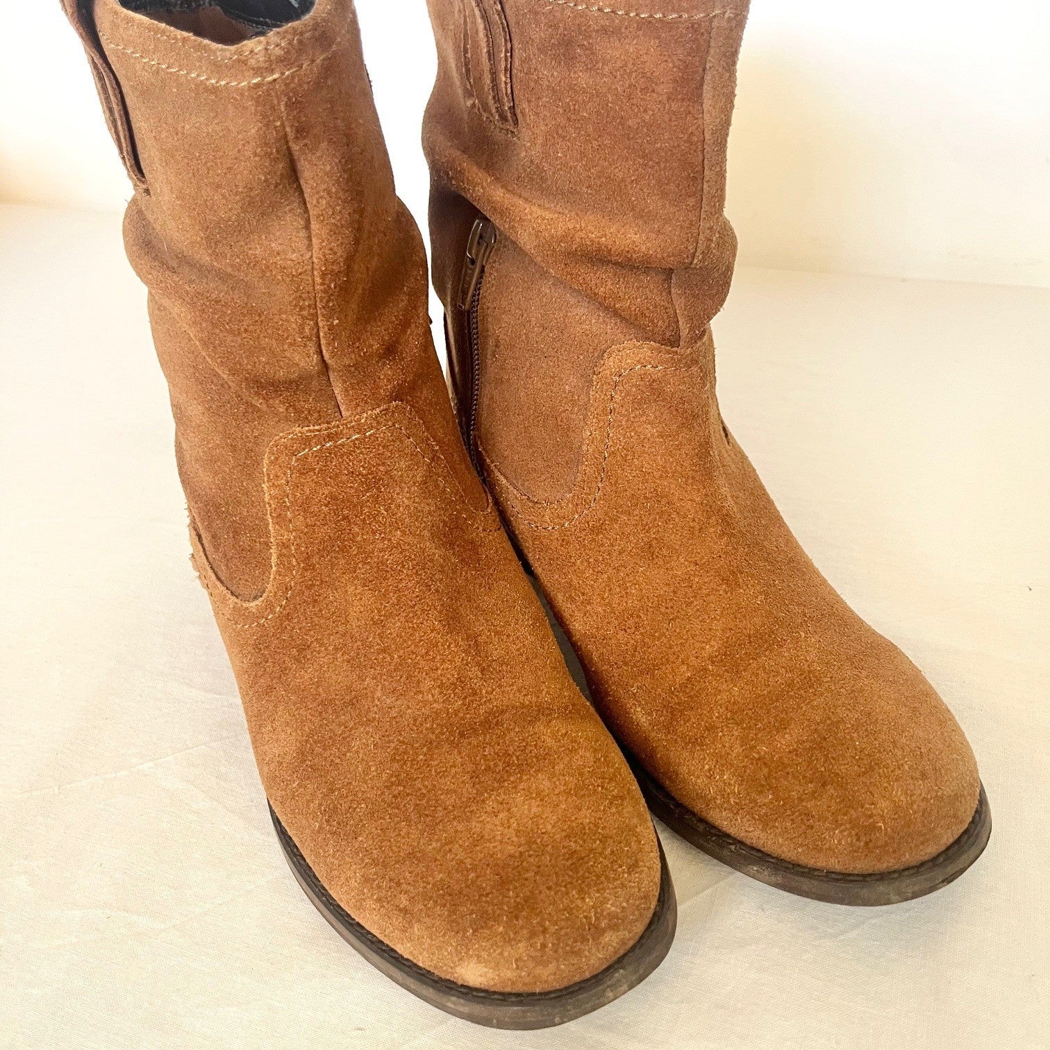 Pair of brown suede boots on a light beige background