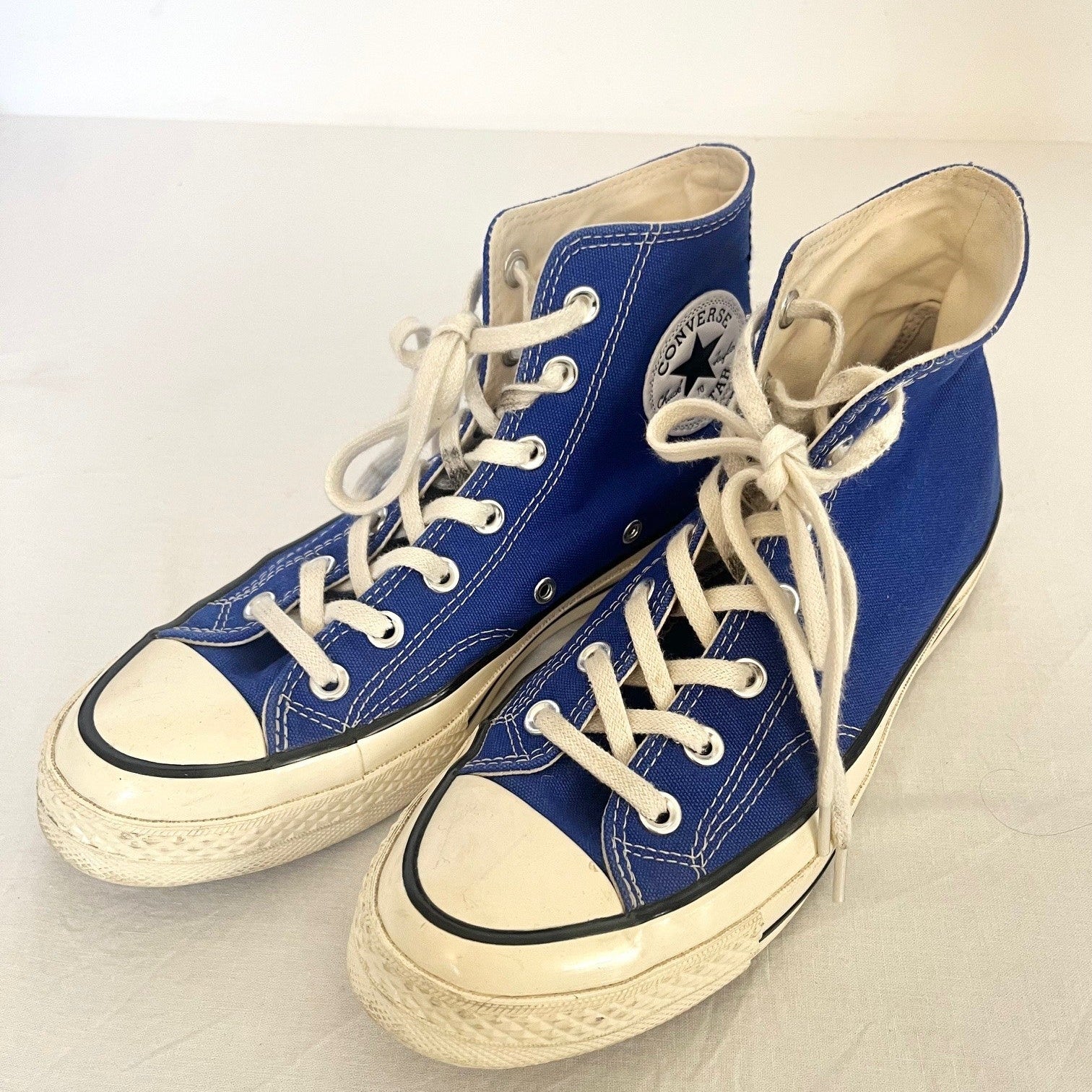 Pair of blue high-top sneakers with white laces on a light background