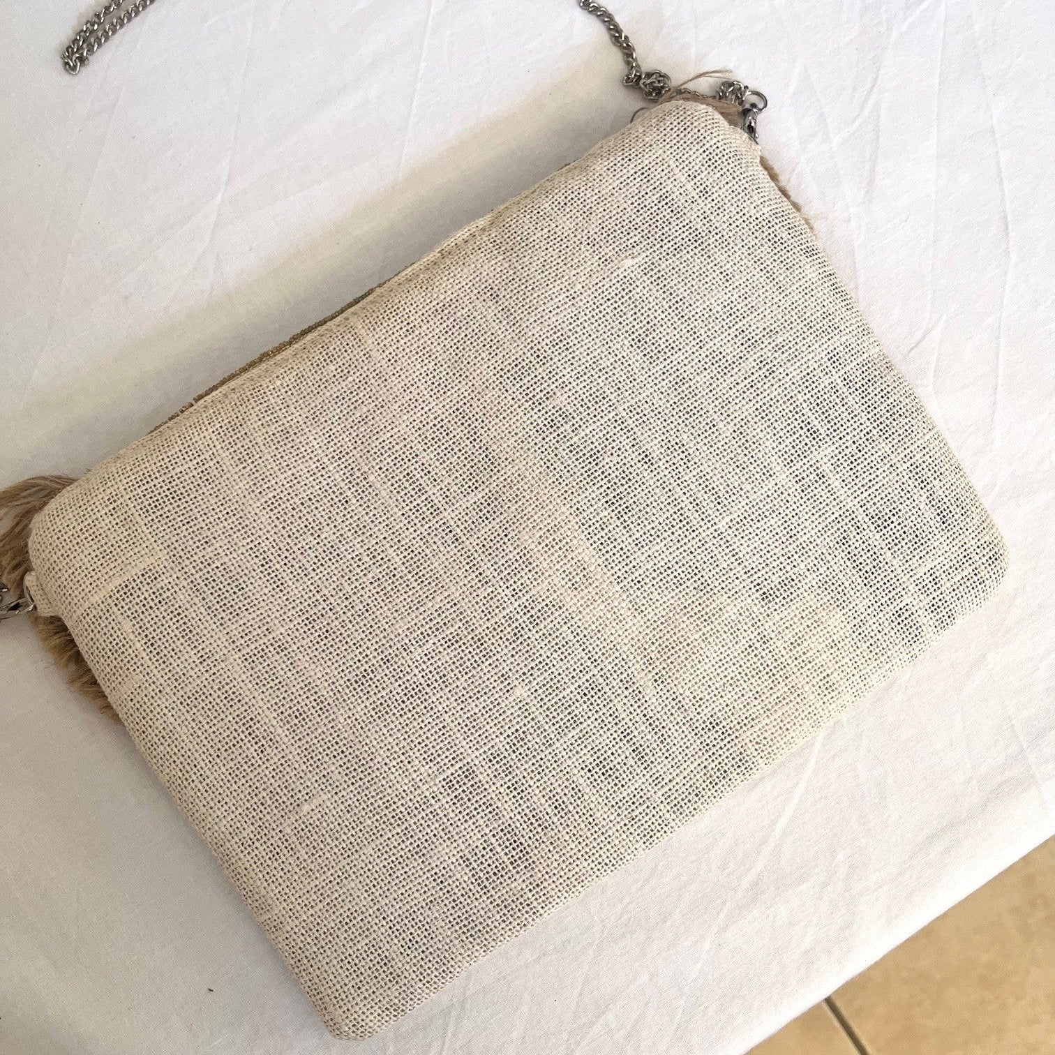 Beige textured clutch bag on a white surface