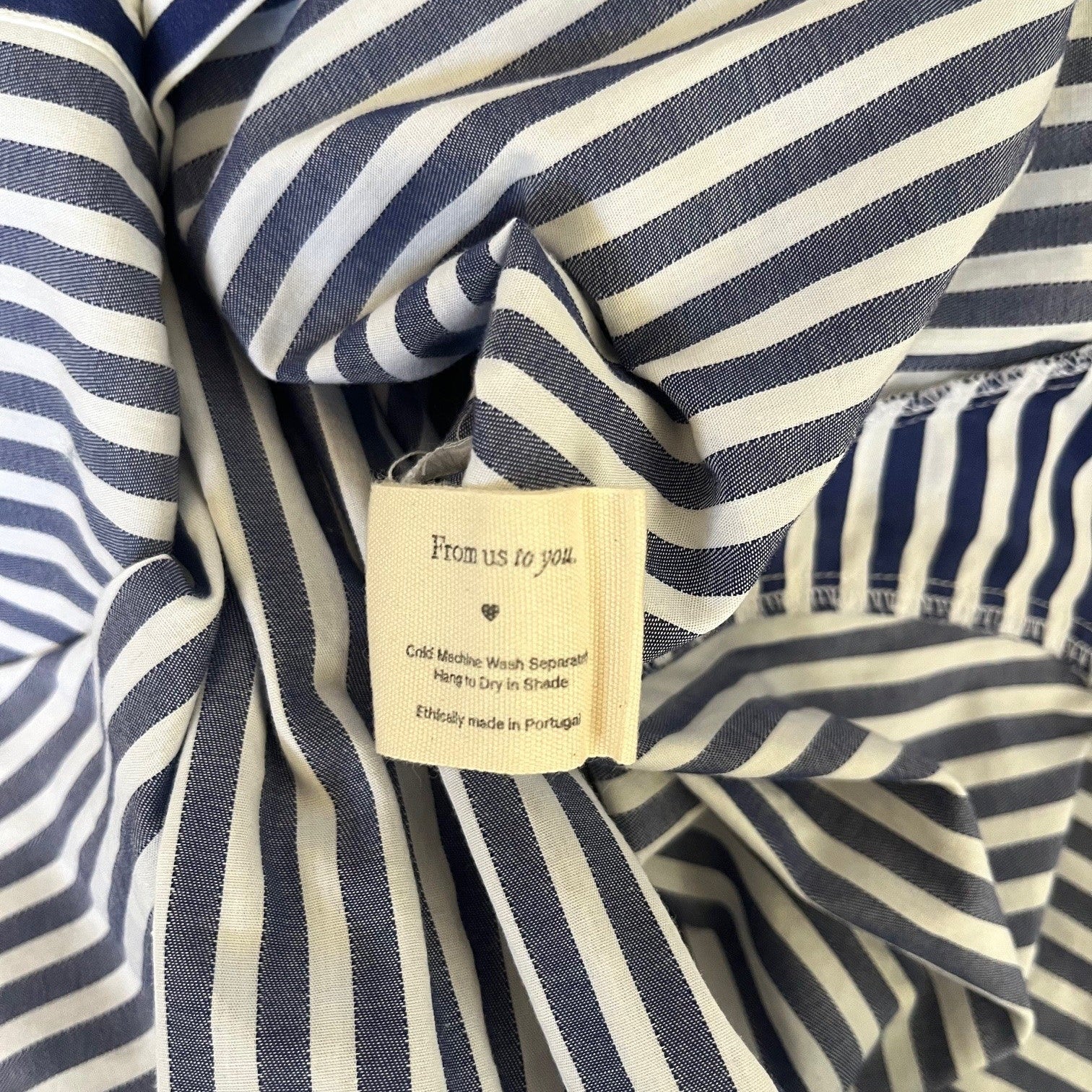 Close-up of a navy and white striped shirt with a tag on a matching fabric background