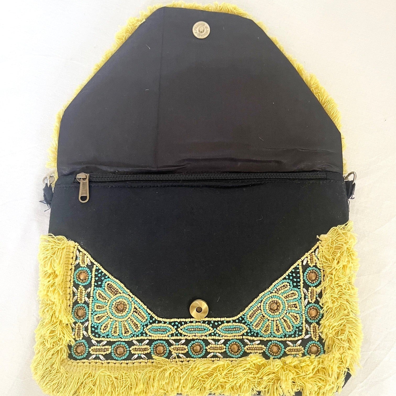 Black clutch bag with yellow and green embroidery on a white background
