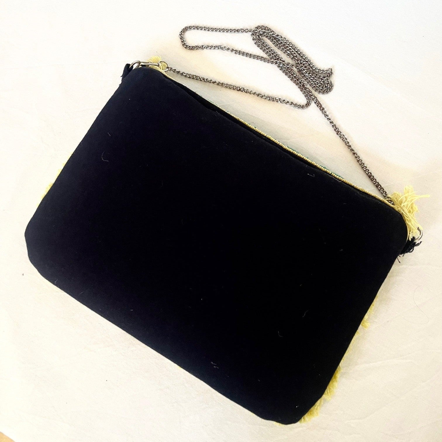 Black clutch bag with a chain strap on a white background